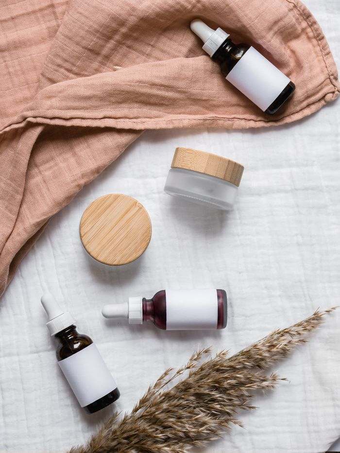 Unbranded skincare jars and a dropper bottle resting on soft linen.
